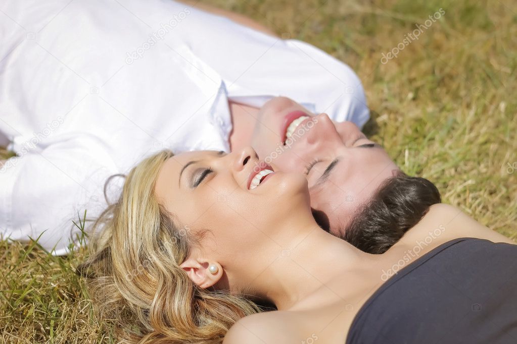 Love couple laughing lying on grass in summer day