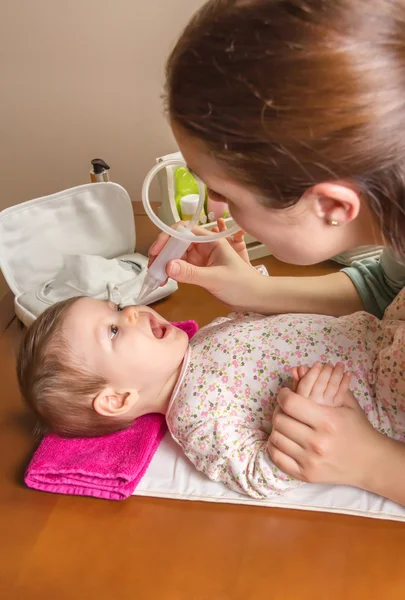 Mother cleaning mucus of baby with nasal aspirator — Stock Photo, Image