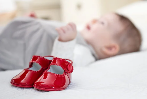 Baby red shoes and babe lying on the background — Stock Photo, Image