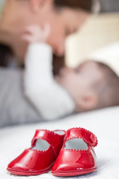 Baby red shoes pair and babe on the background — Stock Photo, Image