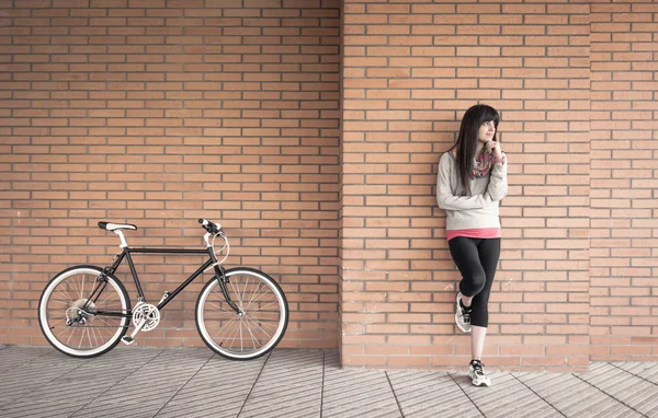 Спортивная женщина с крепким велосипедом над кирпичной стеной — стоковое фото