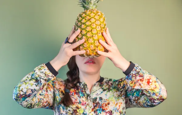 Modemädchen mit Ananas vor dem Gesicht — Stockfoto