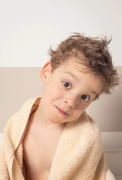 Menino doce com cabelo molhado sob a toalha após o banho — Fotografia de Stock
