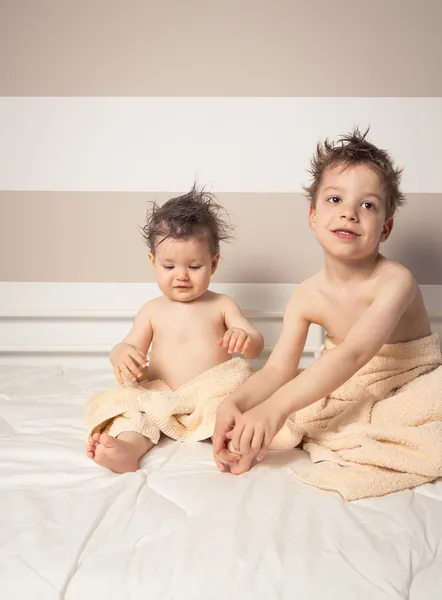 Niño y bebé con el pelo mojado bajo las toallas jugando — Foto de Stock