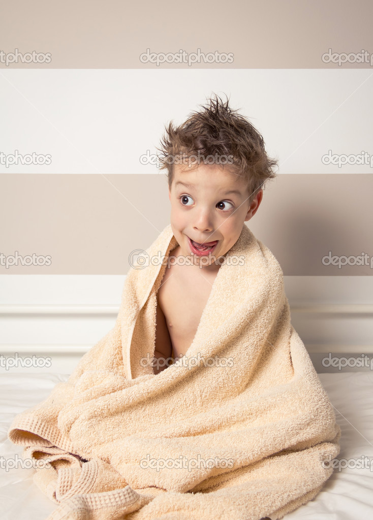 Sweet boy with wet hair under the towel after bath