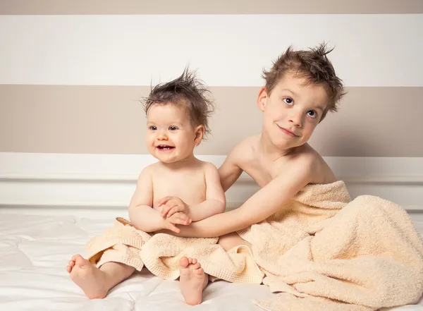 Niño y bebé con el pelo mojado bajo las toallas jugando — Foto de Stock