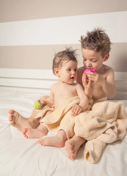 Pojke och baby med blött hår under handdukar spelar — Stockfoto