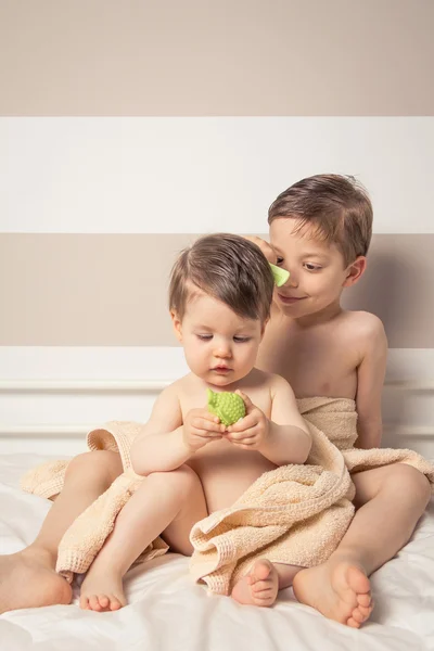 Menino doce pentear menina em uma cama depois do banho — Fotografia de Stock