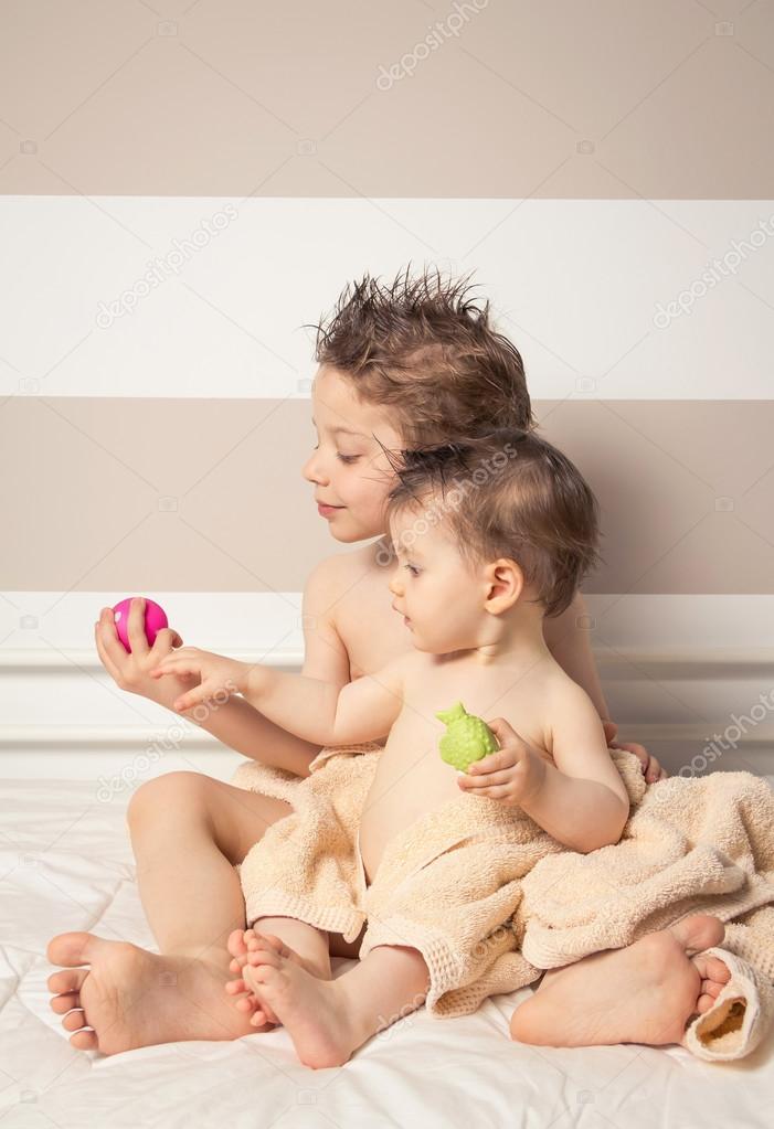 Boy and baby with wet hair under towels playing