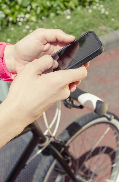嬉戏女人寻找智能手机的单手自行车 — 图库照片