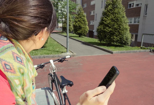 Mulher esportiva com fixie bike procurando smartphone — Fotografia de Stock