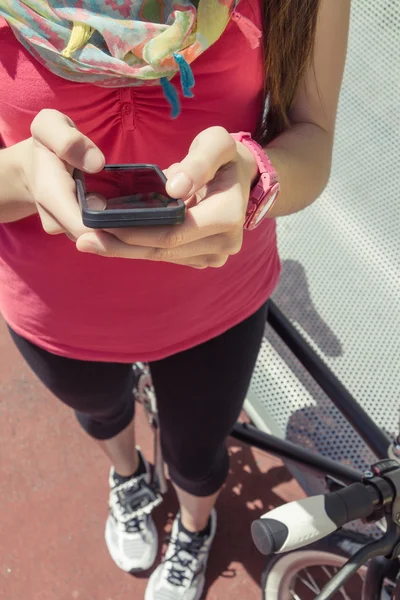 Sportiga kvinnan med fixie cykel söker smartphone — Stockfoto