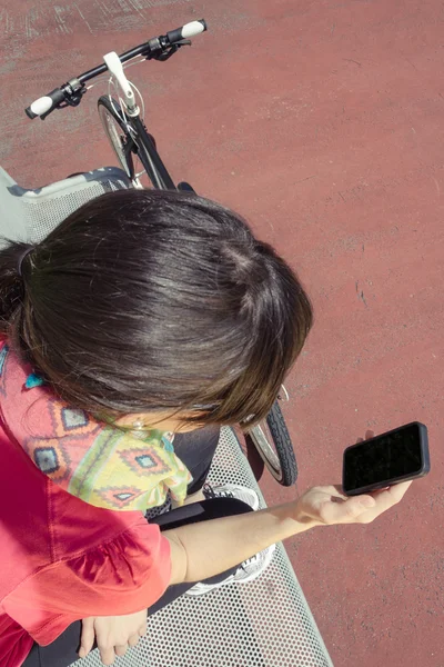 Sportiga kvinnan med fixie cykel söker smartphone — Stockfoto
