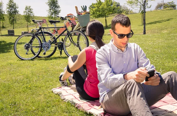 Pasangan yang jatuh cinta menggunakan smartphone di taman — Stok Foto