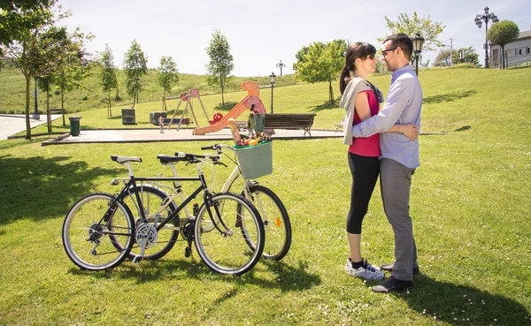 Пара влюбленных, обнятых рядом с велосипедами в парке — стоковое фото