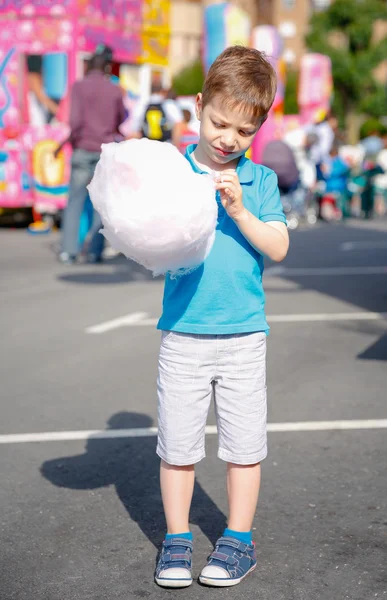 Lindo niño comiendo algodón de azúcar sobre fondo justo — Foto de Stock