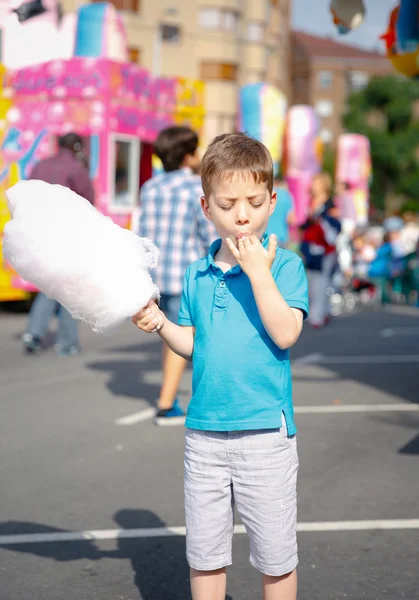 Lindo niño comiendo algodón de azúcar sobre fondo justo — Foto de Stock