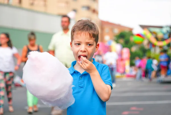 Miúdo bonito comendo algodão doce sobre fundo justo — Fotografia de Stock