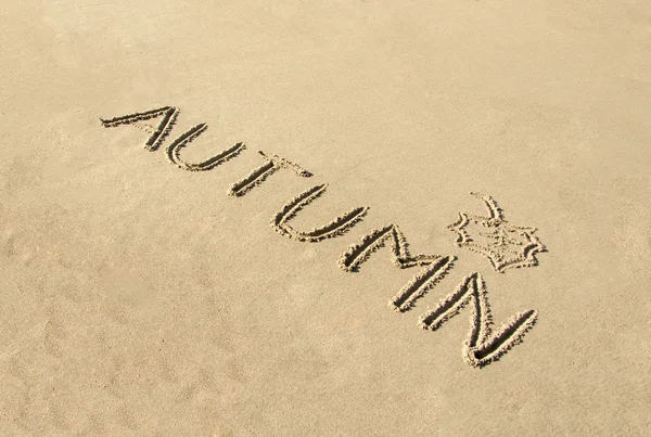 Woord herfst handgeschreven en blad in zand getrokken — Stockfoto