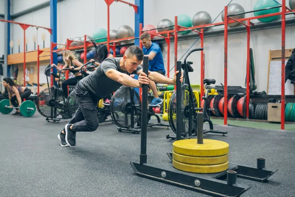 Allenamento uomo in palestra con una slitta push — Foto Stock