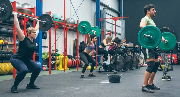 Personas que practican levantamiento de pesas levantando pesas en el gimnasio — Foto de Stock