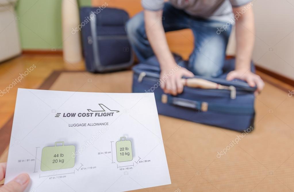 Man trying to close full hand luggage