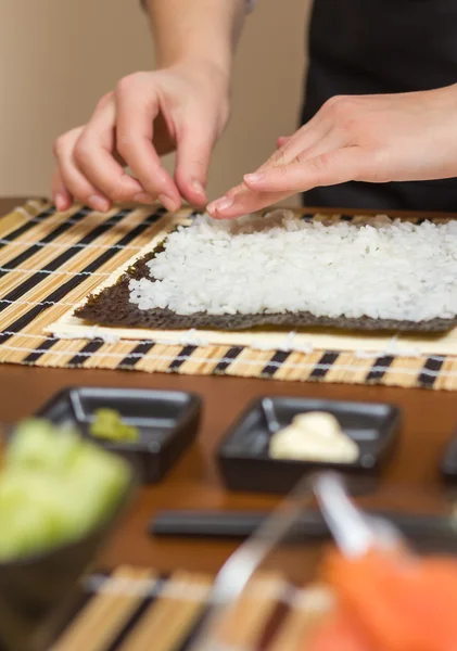 Mains de femme chef remplissant des rouleaux de sushi japonais avec du riz — Photo