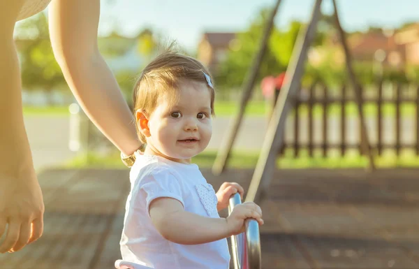 Niña jugando sobre un columpio en el parque —  Fotos de Stock