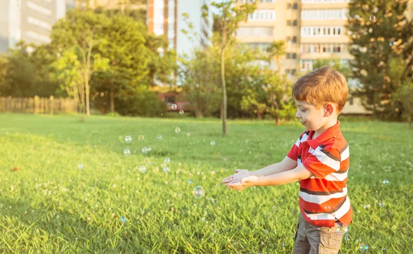 Garçon heureux jouant avec des bulles de savon dans le parc — Photo