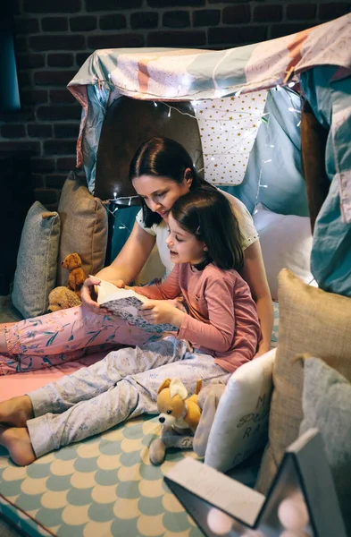 Mor och dotter läser en bok i ett diy tält — Stockfoto