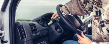 Arabanın torpidosunun tozunu temizleyen genç kadın.