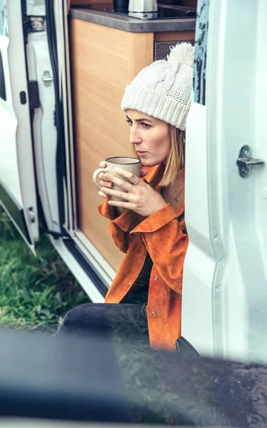 Vrouw die koffie drinkt zittend aan de deur van een camper — Stockfoto