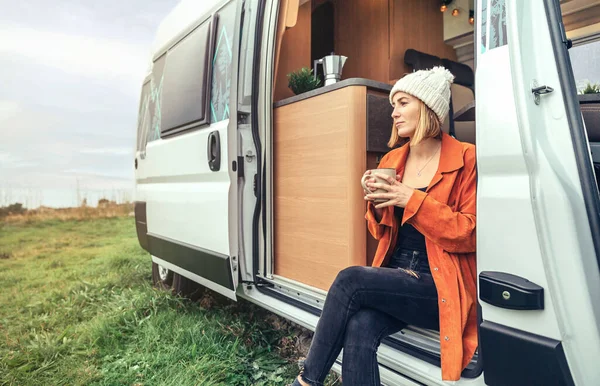 Mulher bebendo café sentado à porta de uma campervan — Fotografia de Stock