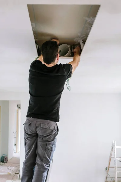 台所の天井に掘削機フードのインストールを準備する男 — ストック写真