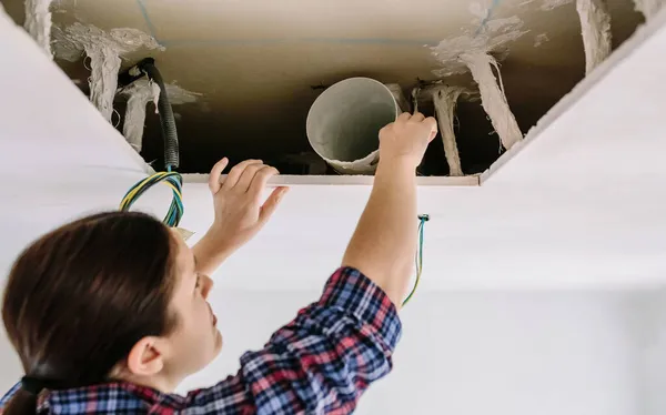 Woman placing tube for kitchen hood installation — Stock Photo, Image