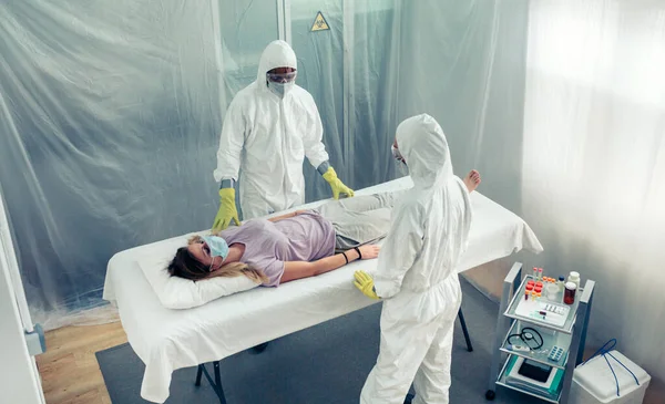 Médicos em proteção bacteriológica observando um paciente deitado em uma maca — Fotografia de Stock