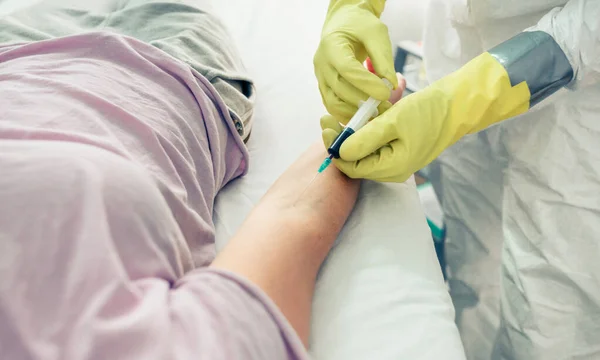 Dokter neemt bloedmonster van de patiënt liggend op de brancard — Stockfoto