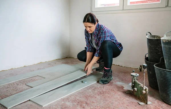 바닥을 설치하기 위해 타일을 놓는 여자 벽돌공 — 스톡 사진