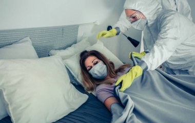 Bakteriyolojik koruyucu giysiler giyen doktorlar bir hastayla ilgileniyorlar.