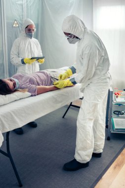 Doktorlar sedyede yatan hastadan kan örneği alıyorlar.