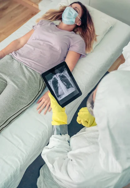 Arzt im Schutzanzug untersucht Röntgenbild des Patienten auf Tablet — Stockfoto