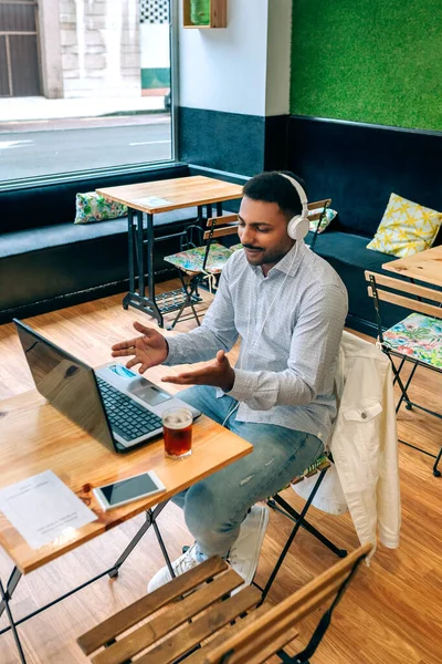 Hombre hablando en videoconferencia con portátil desde la cafetería — Foto de Stock