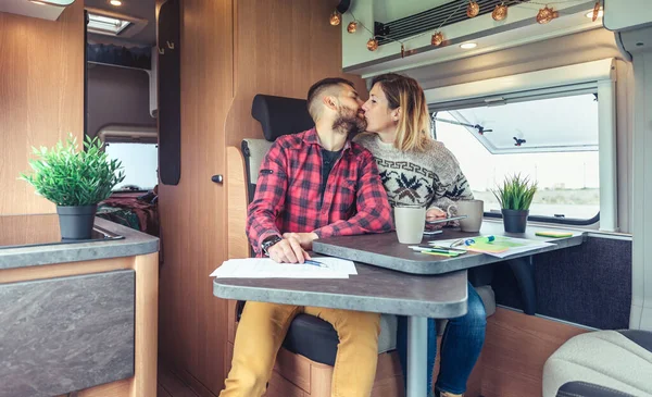 Couple kissing while telecommuting in a camper van — ストック写真