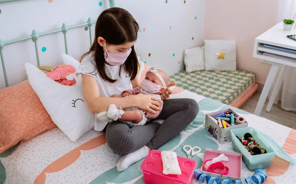 Mädchen mit Maske spielt, um sich um ihre Puppe mit Maske zu kümmern — Stockfoto