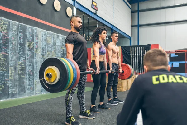 Mixed team lifting weights in the gym with their coach — Stock Photo, Image