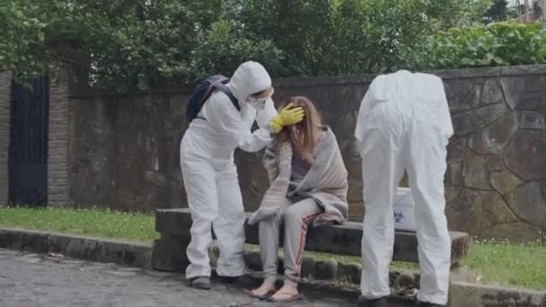 Doctors in protection suits caring woman — 图库视频影像