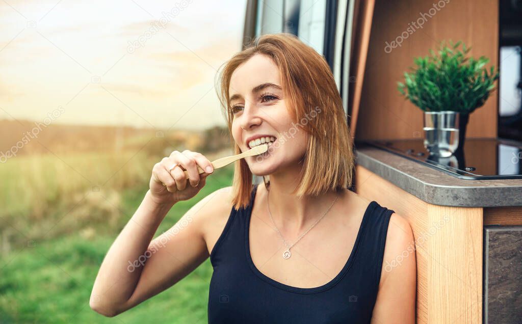 Woman brushing her teeth with a bamboo toothbrush outdoors