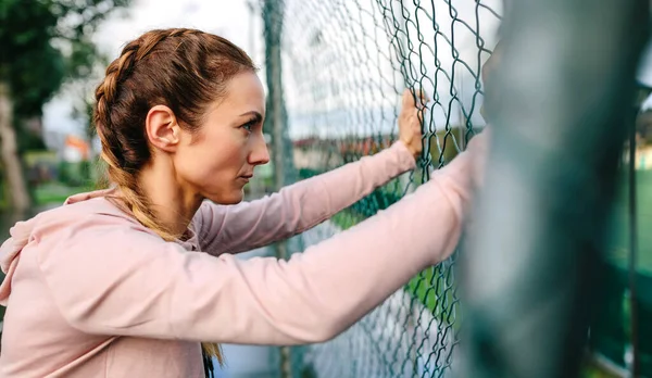 真剣なportswomenとともにボクサー編組金属フェンスにもたれて — ストック写真