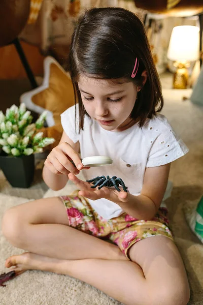 Menina jogando observando insetos de brinquedo com uma lupa — Fotografia de Stock