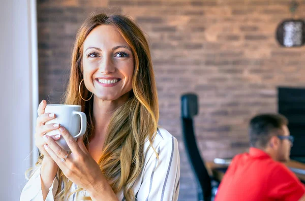 Счастливая деловая женщина смотрит в камеру с чашкой кофе — стоковое фото